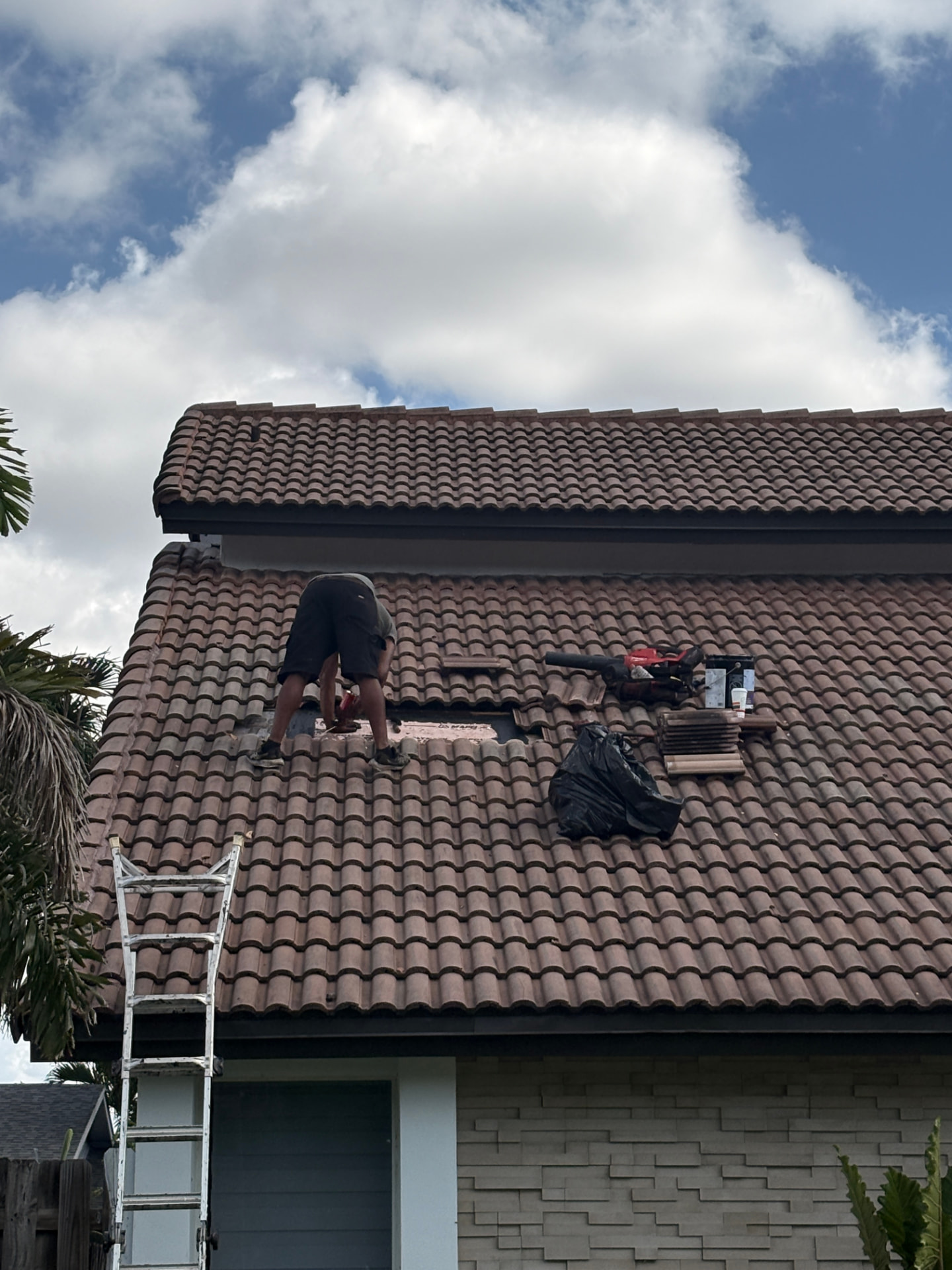 Roofer repairing barrel tile roof section