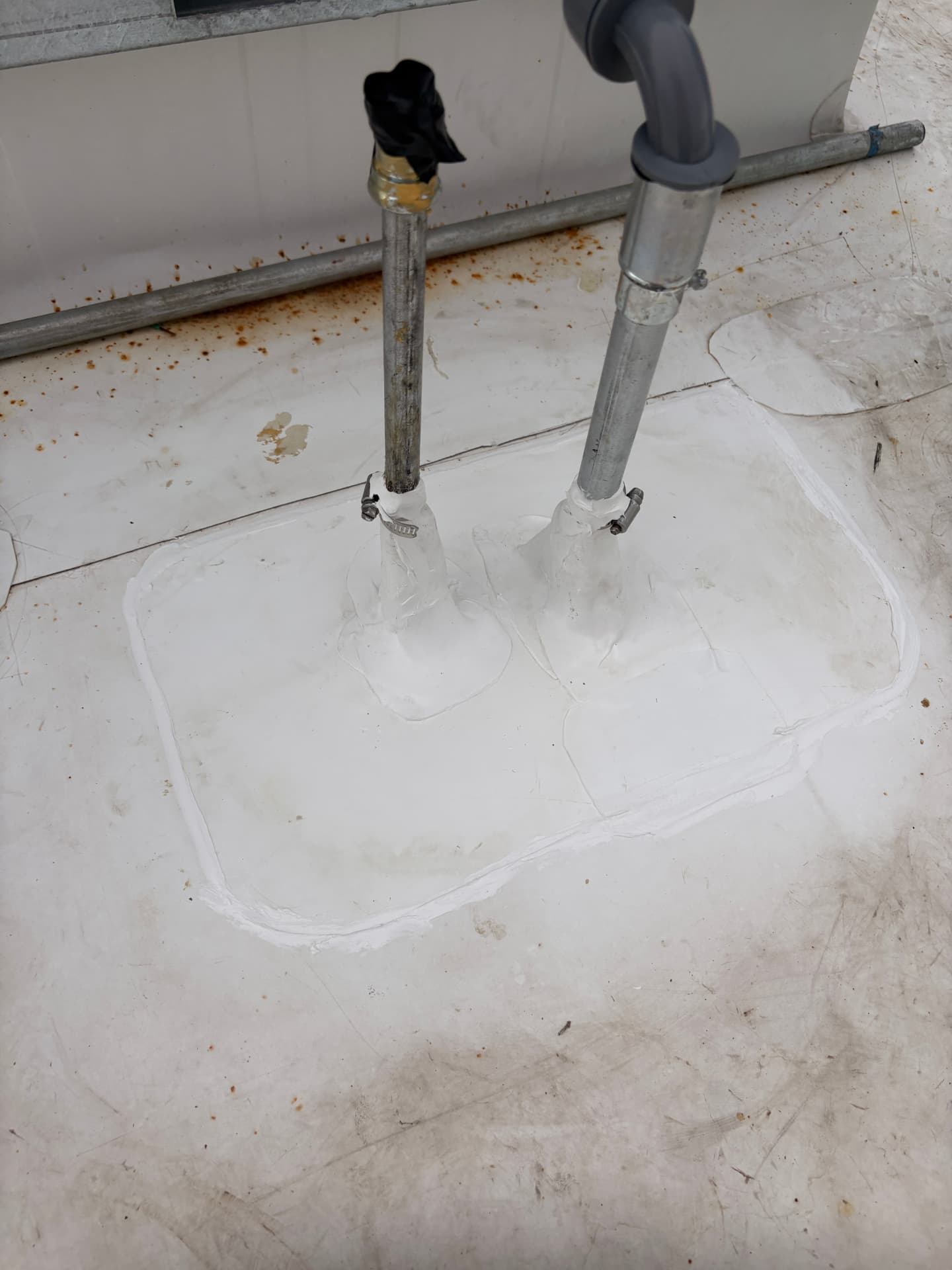 Sealed pipe penetrations on a white flat roof membrane